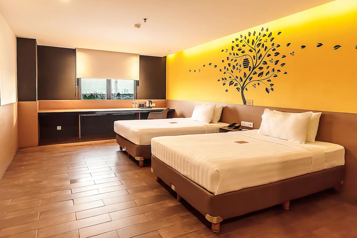 Quarto de hotel moderno com duas camas, uma kitchenette pequena e uma janela grande.