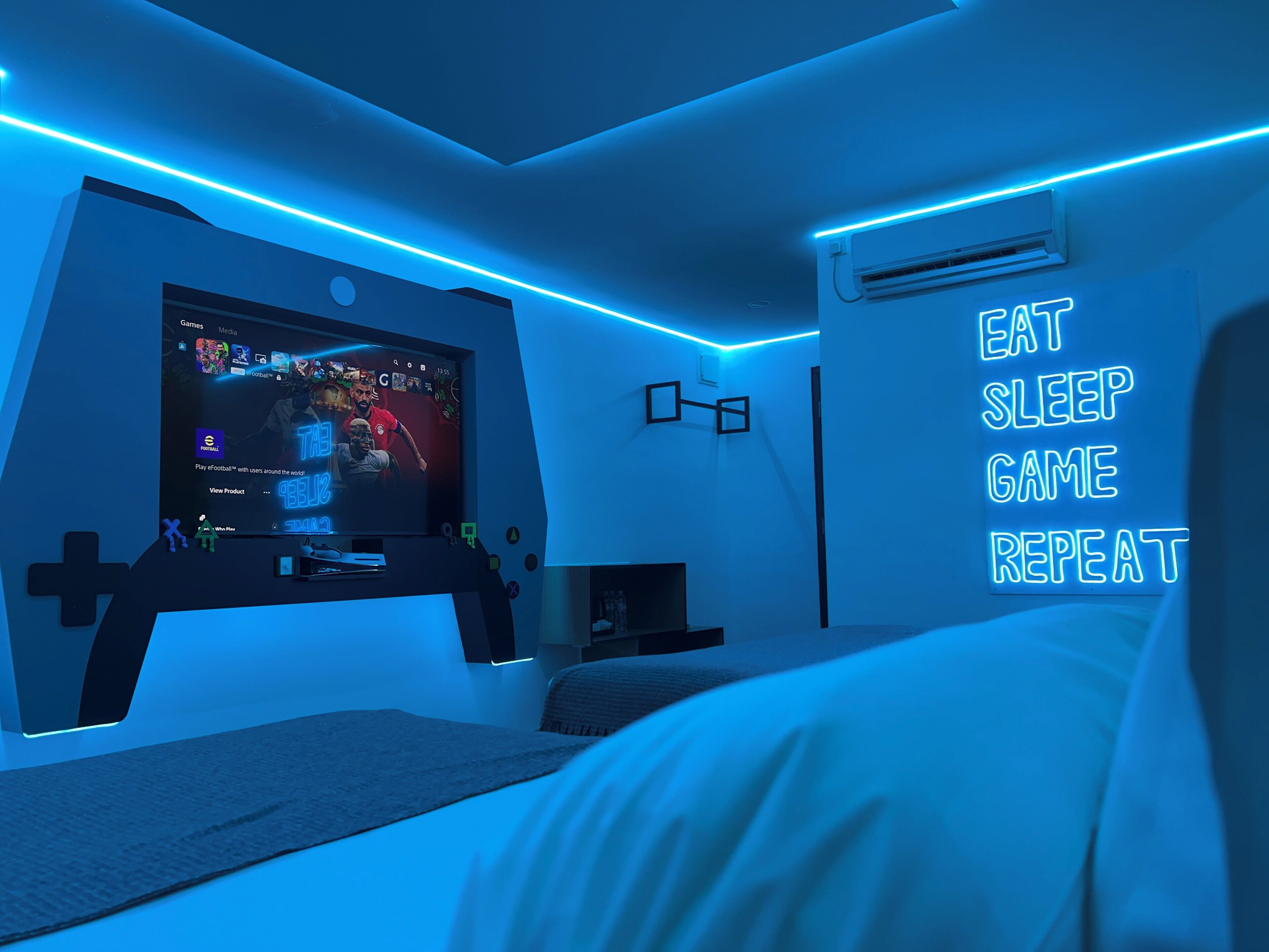Une chambre moderne avec une grande télévision, un néon et un lit.