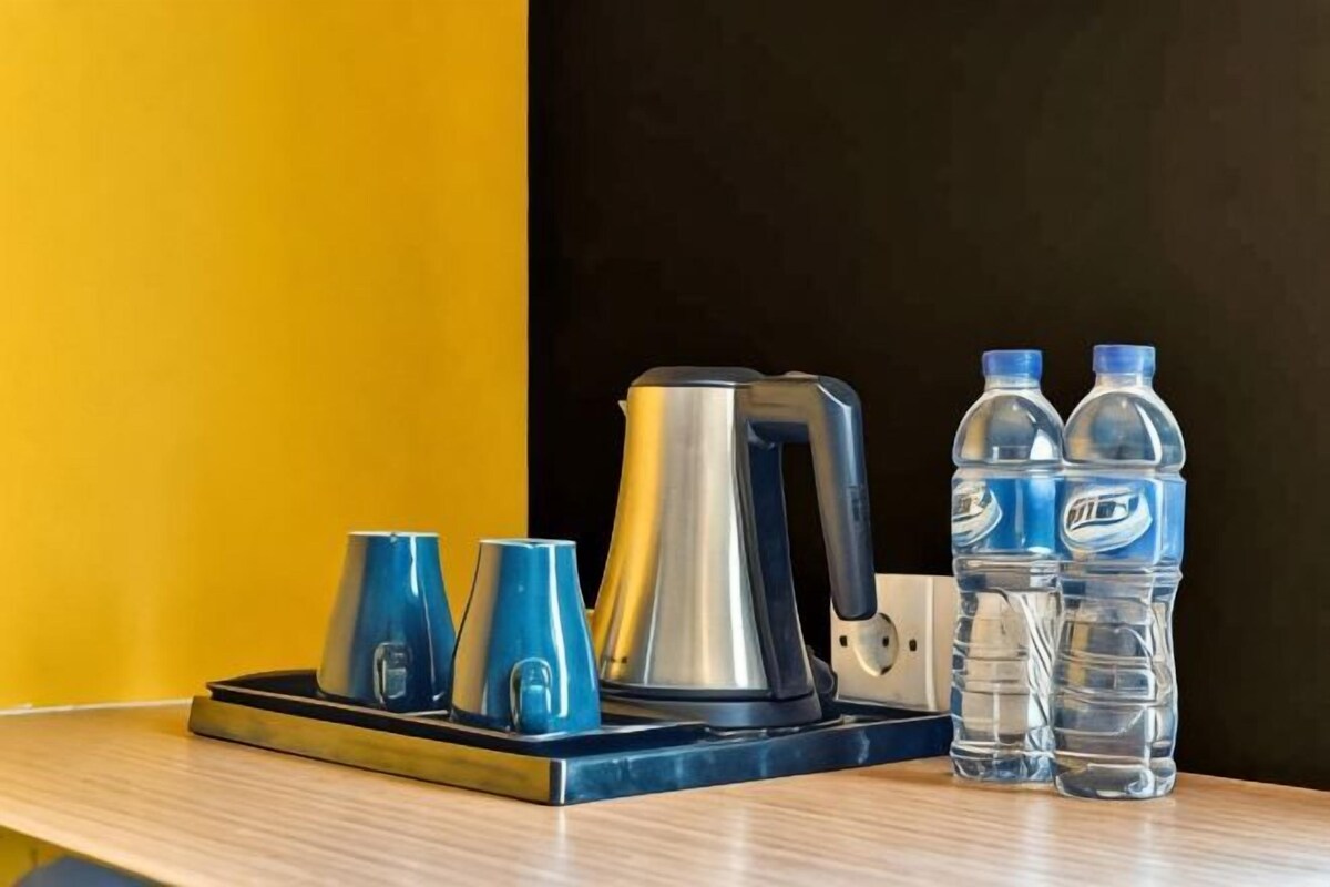 A coffee maker, two cups, and two water bottles on a tray.