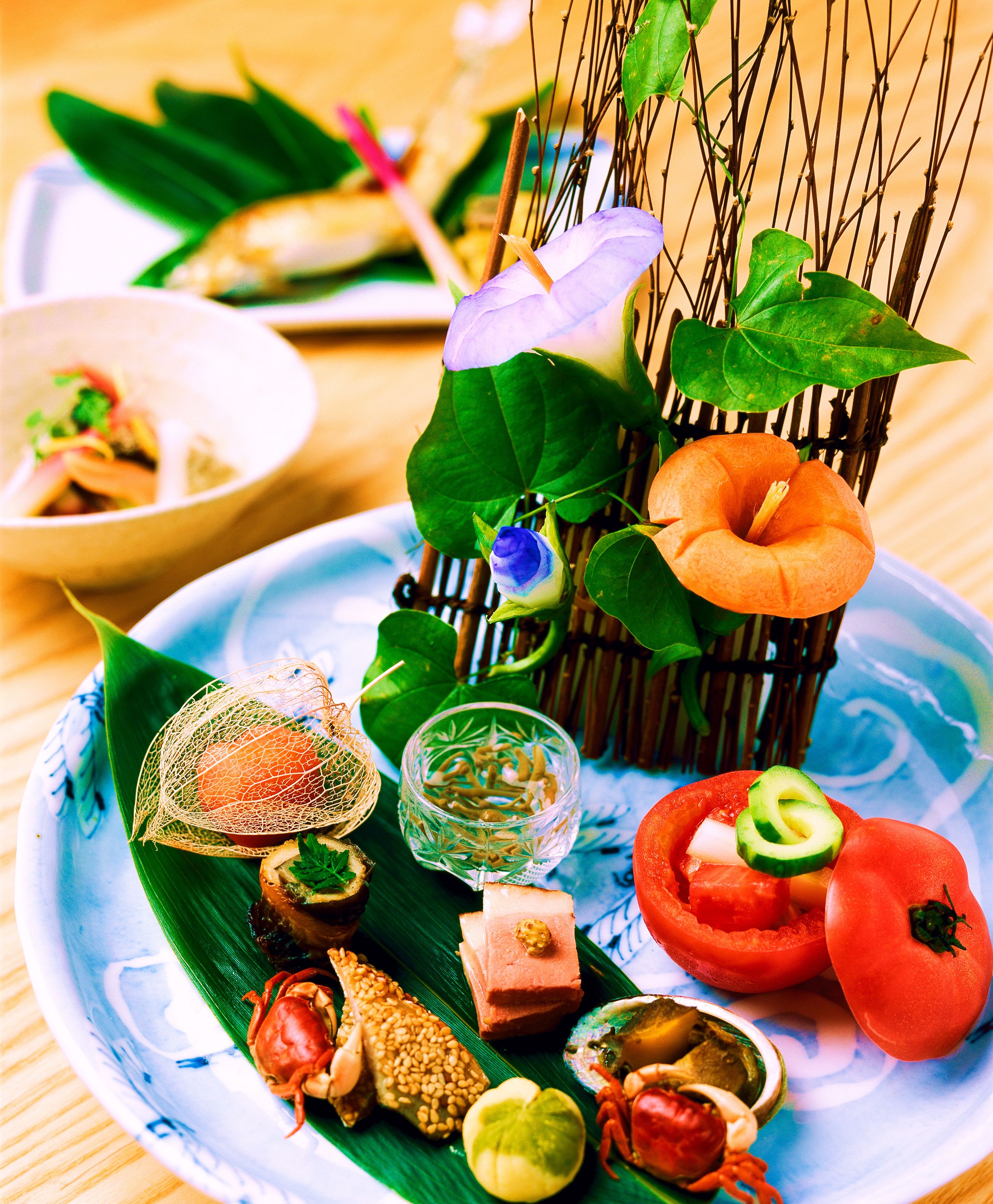 A plate with various food items including a crab, avocado, and a tomato.