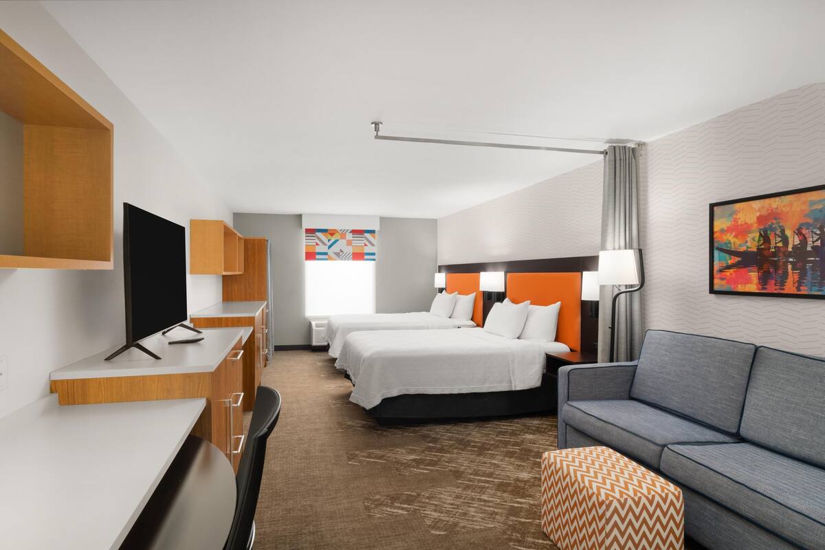 Una habitación de hotel con dos camas, un escritorio, un sofá y una televisión.