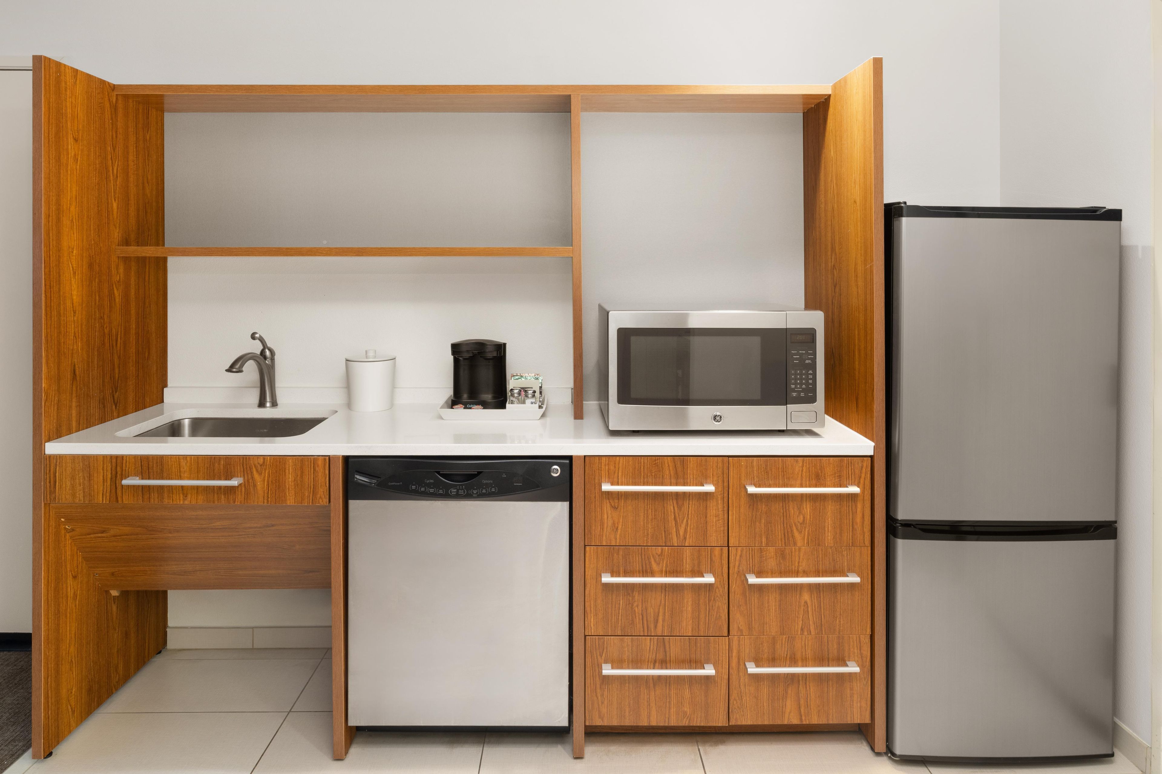 A compact kitchen with a built-in dishwasher, a microwave, and a refrigerator.