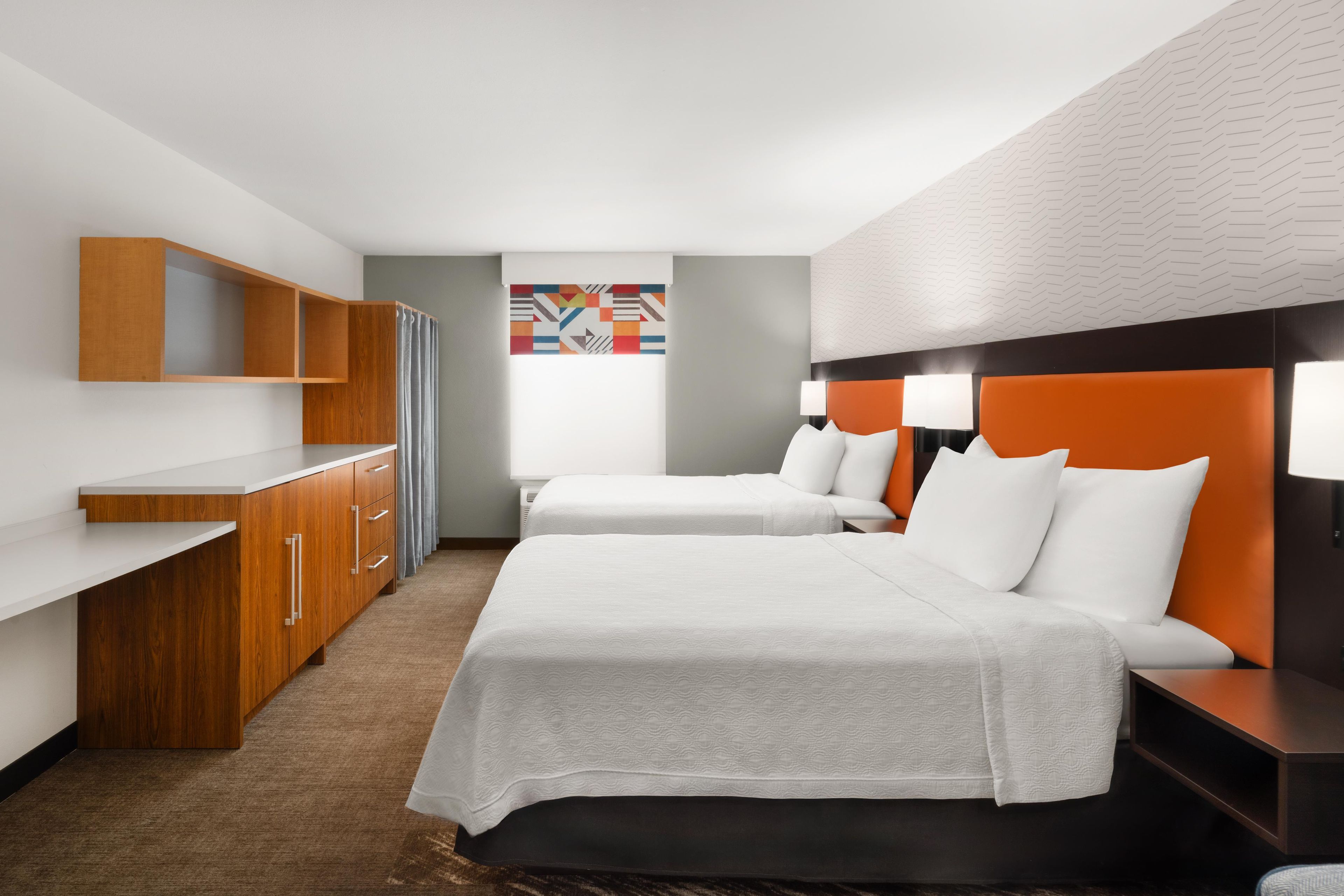 A hotel room with two beds, a desk, and a wardrobe.