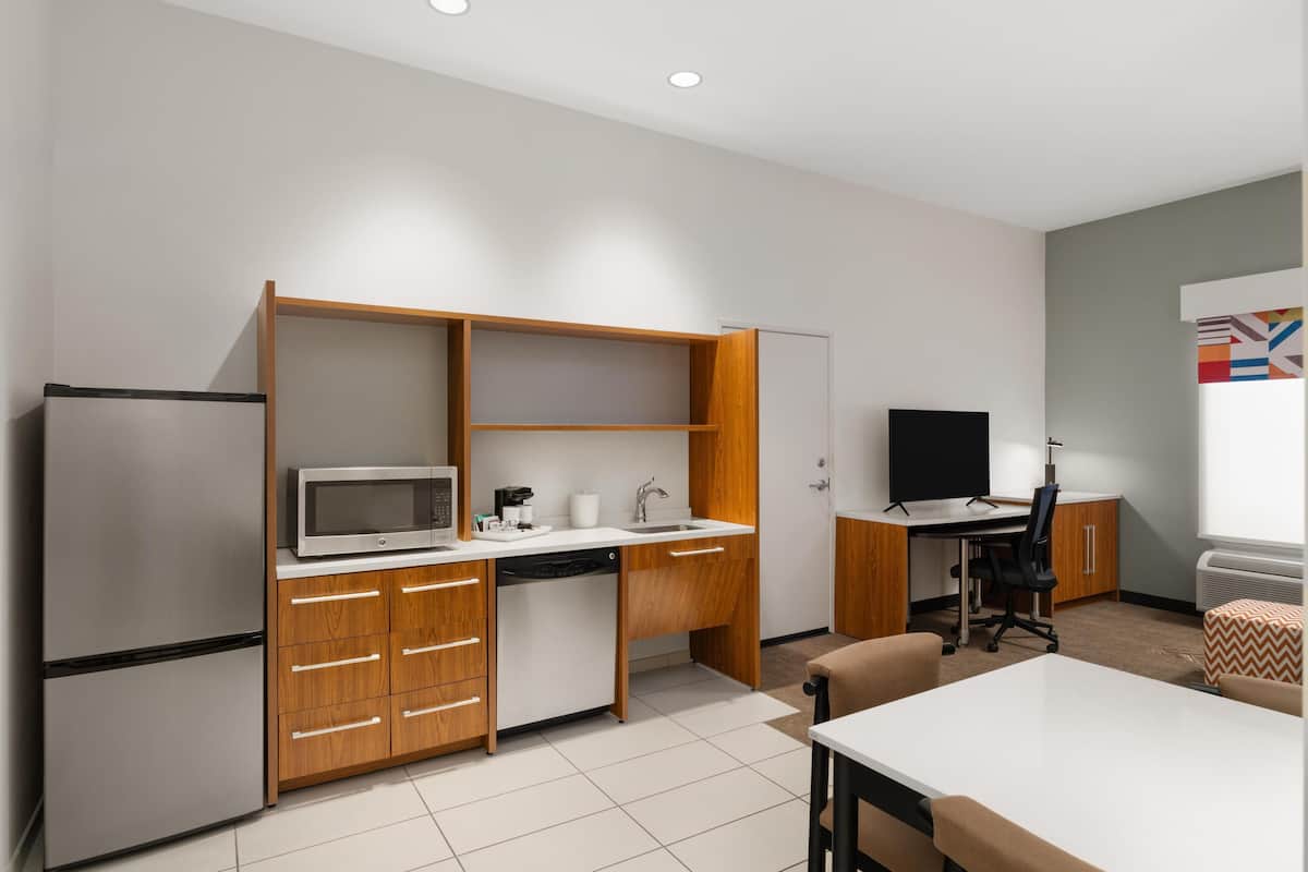 Cocina compacta con microondas, pileta y armarios de madera.