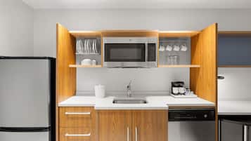 Una cocina compacta con microondas integrado, cafetera y lavavajillas.