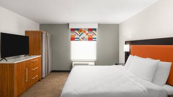 A hotel room with a bed, a TV, a wardrobe, a window with curtains, and a wall with a herringbone pattern.