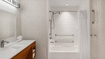 A modern bathroom with a dual sink vanity, a freestanding bathtub, and a shower with a handheld showerhead.