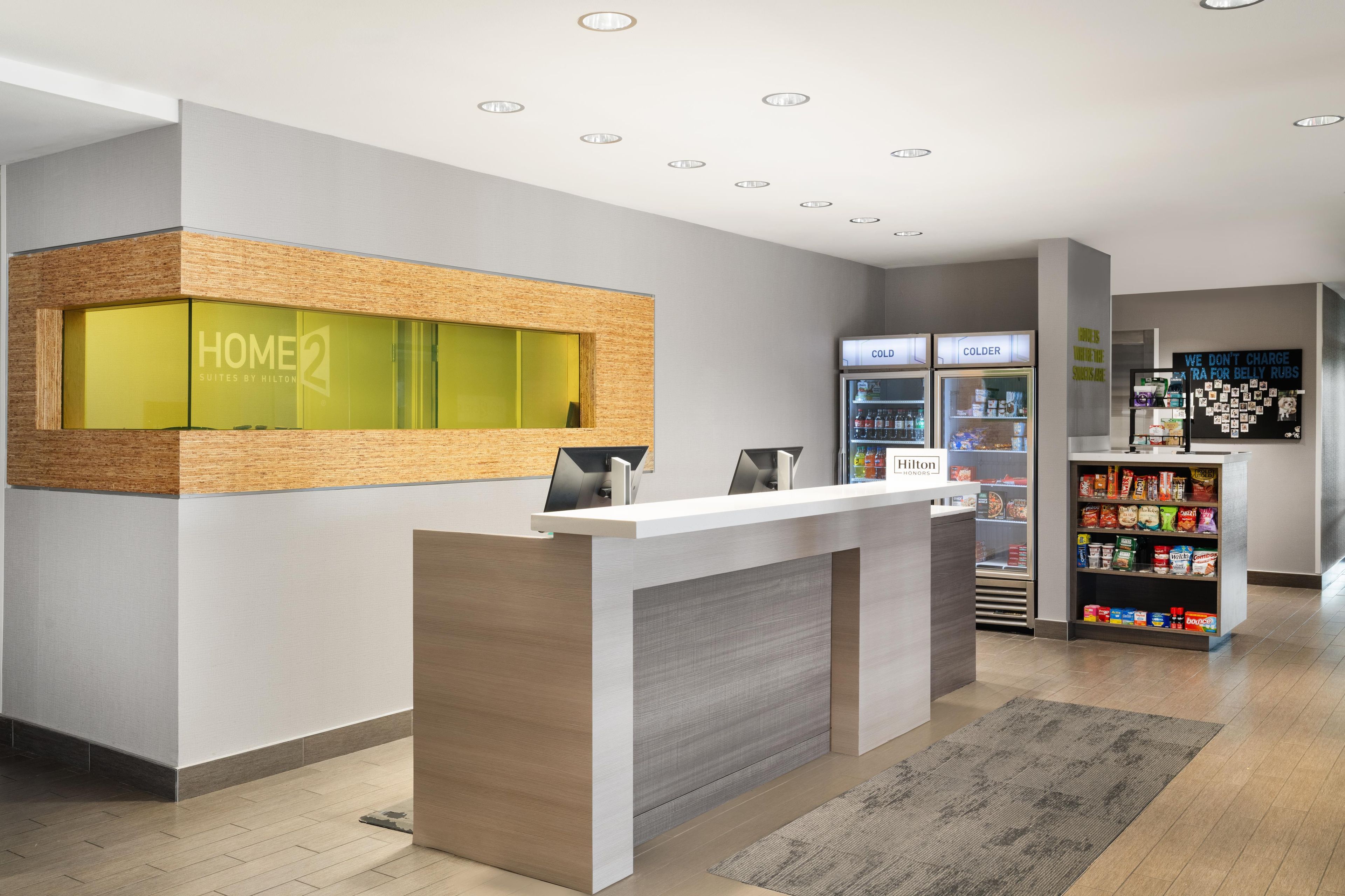 A hotel reception area with a reception desk, a minibar, and a refrigerator.