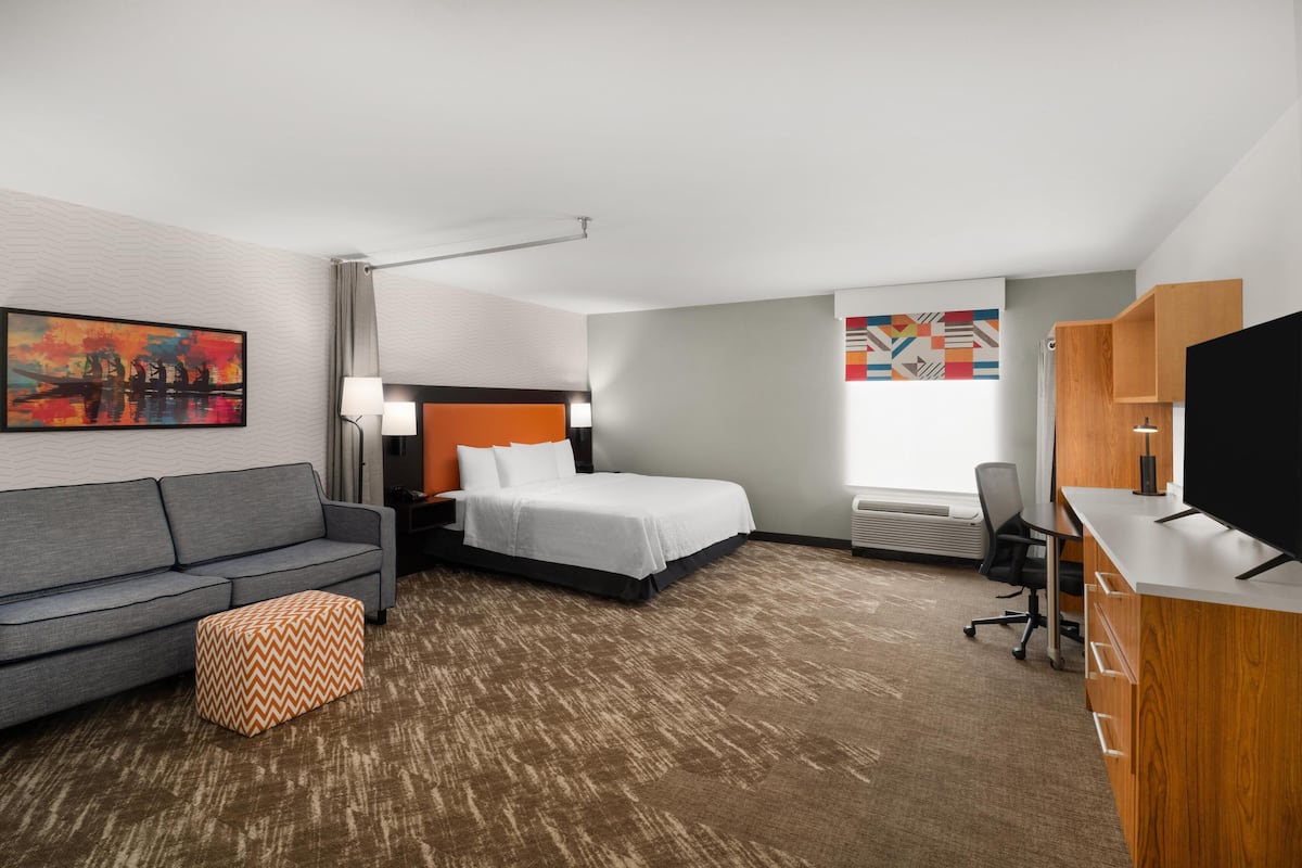 Habitación de hotel con cama, sofá, escritorio y televisor.