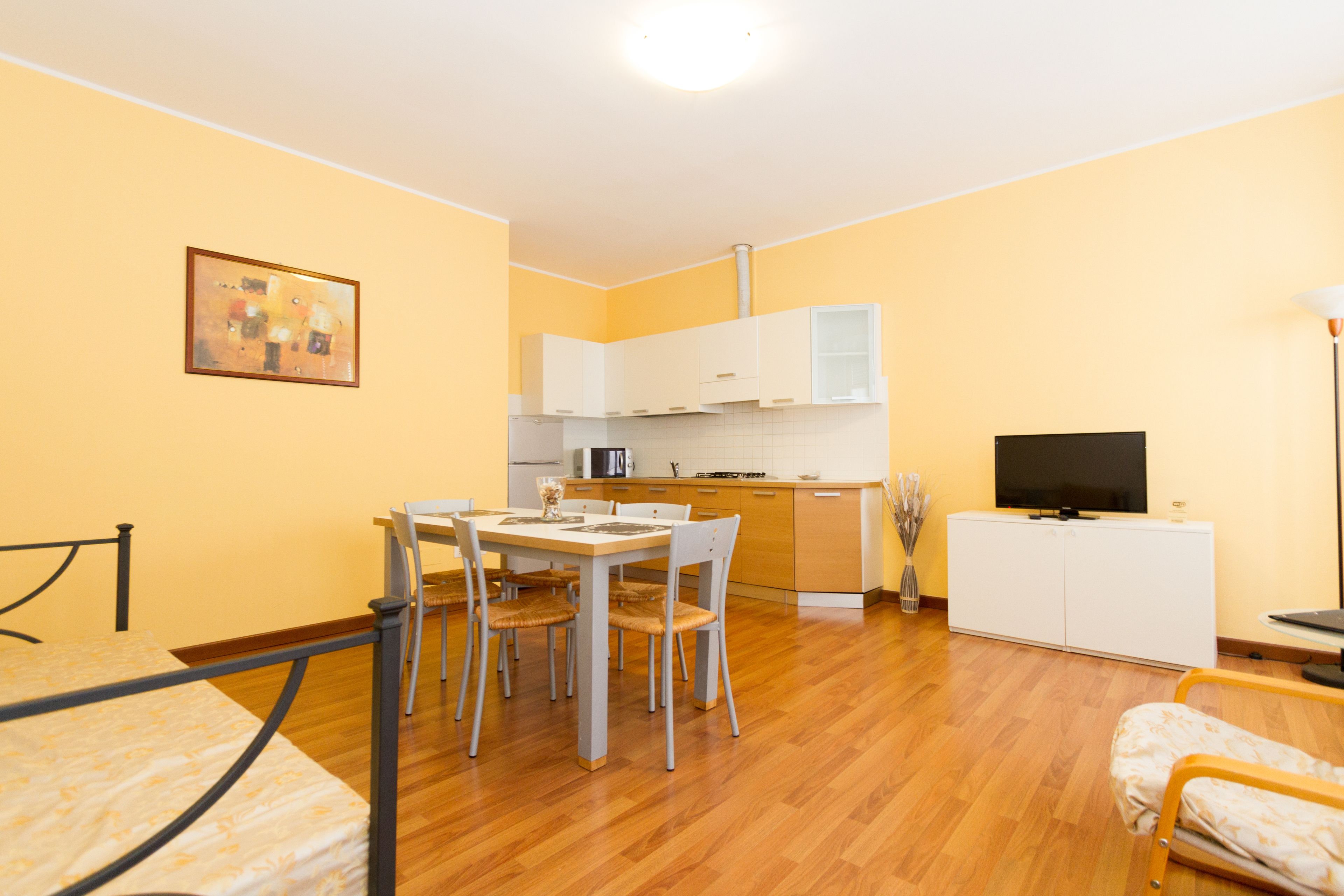 A compact living space with a dining area, kitchenette, and a television.
