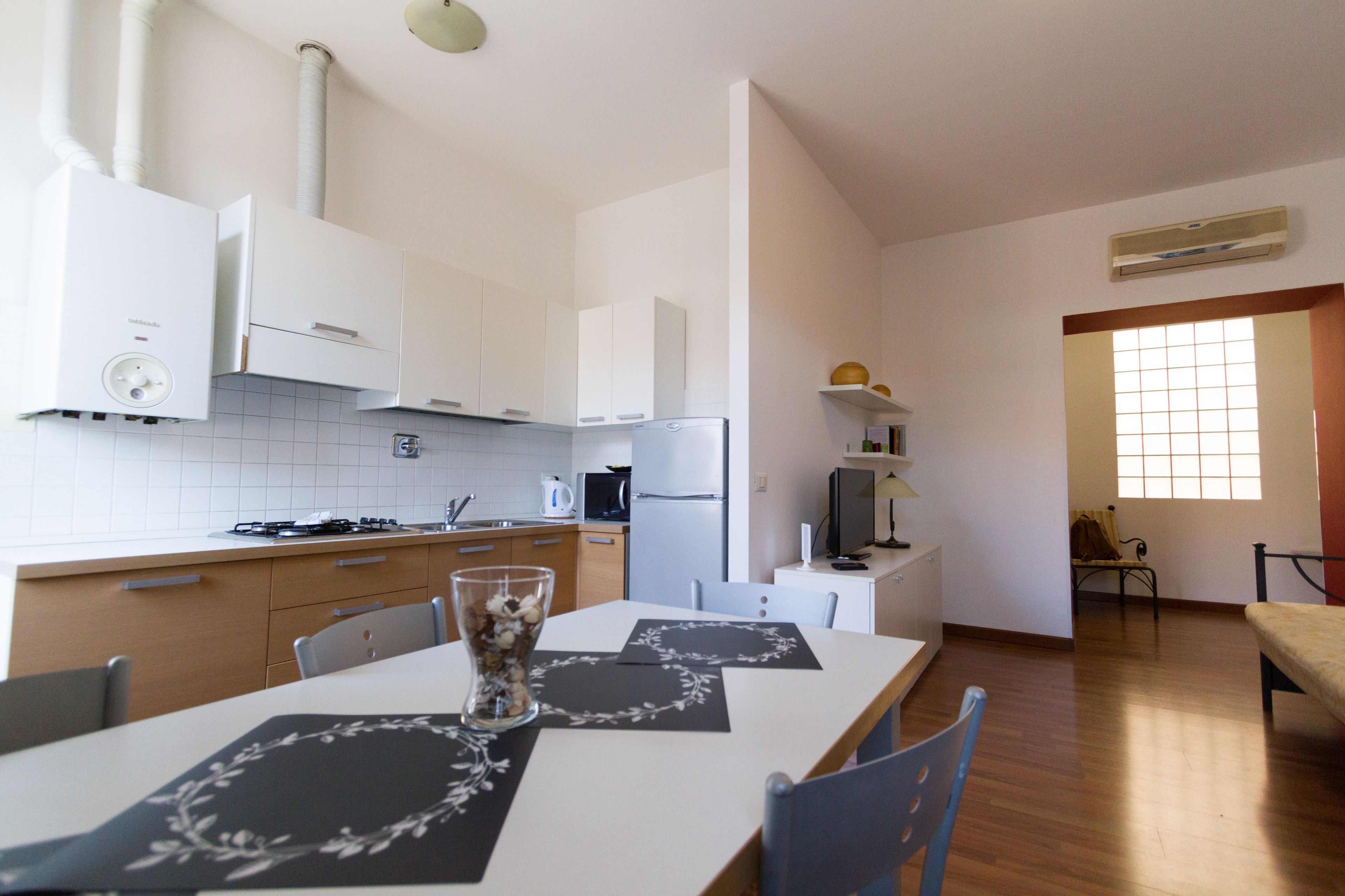 A modern kitchen with white cabinets, a stove, and a dining area with a table and chairs.