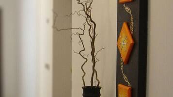 A hallway with a potted plant and decorative wall art.