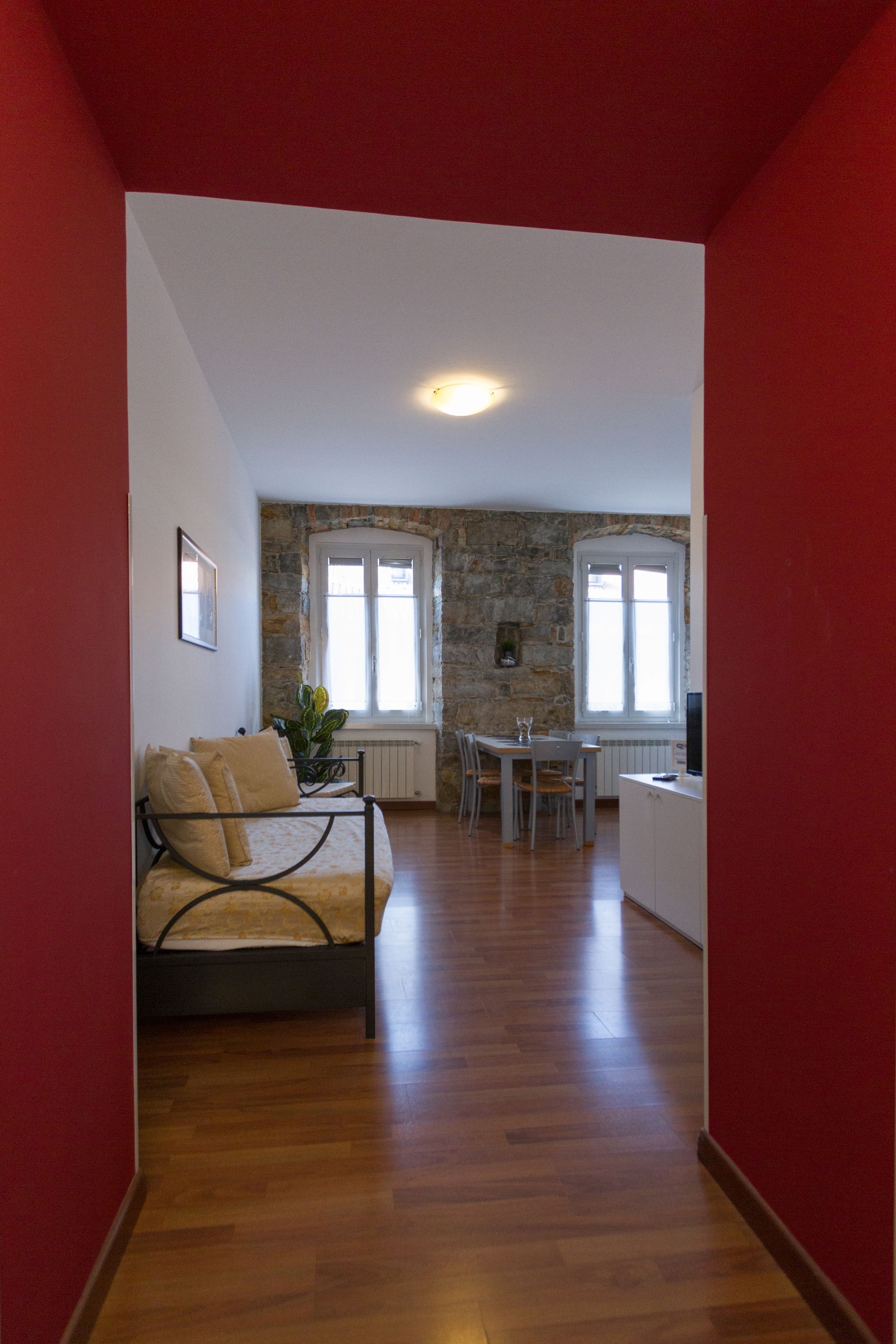 Una habitación con cama, una mesa de comedor con sillas, una pequeña cocina y una pared de piedra.