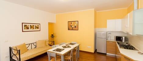 A compact living space with a dining area, kitchenette, and a sofa.