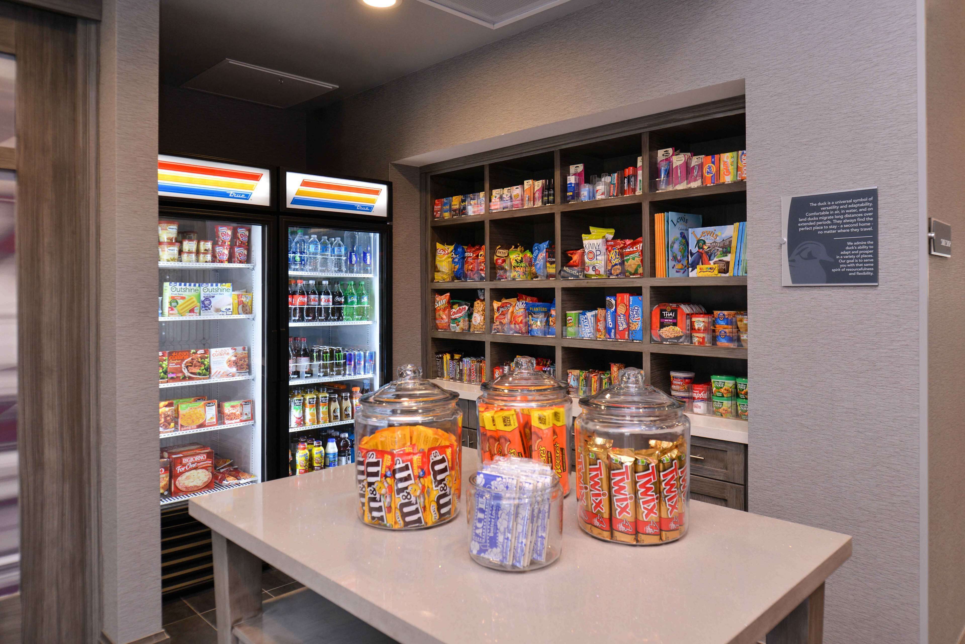 A snack bar with various food items and beverages, including jars of snacks and a refrigerator with drinks.