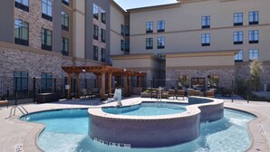 Zona de piscina de hotel con jacuzzi y asientos.