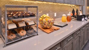 Un bufé de desayuno con bollería, frutas y bebidas.