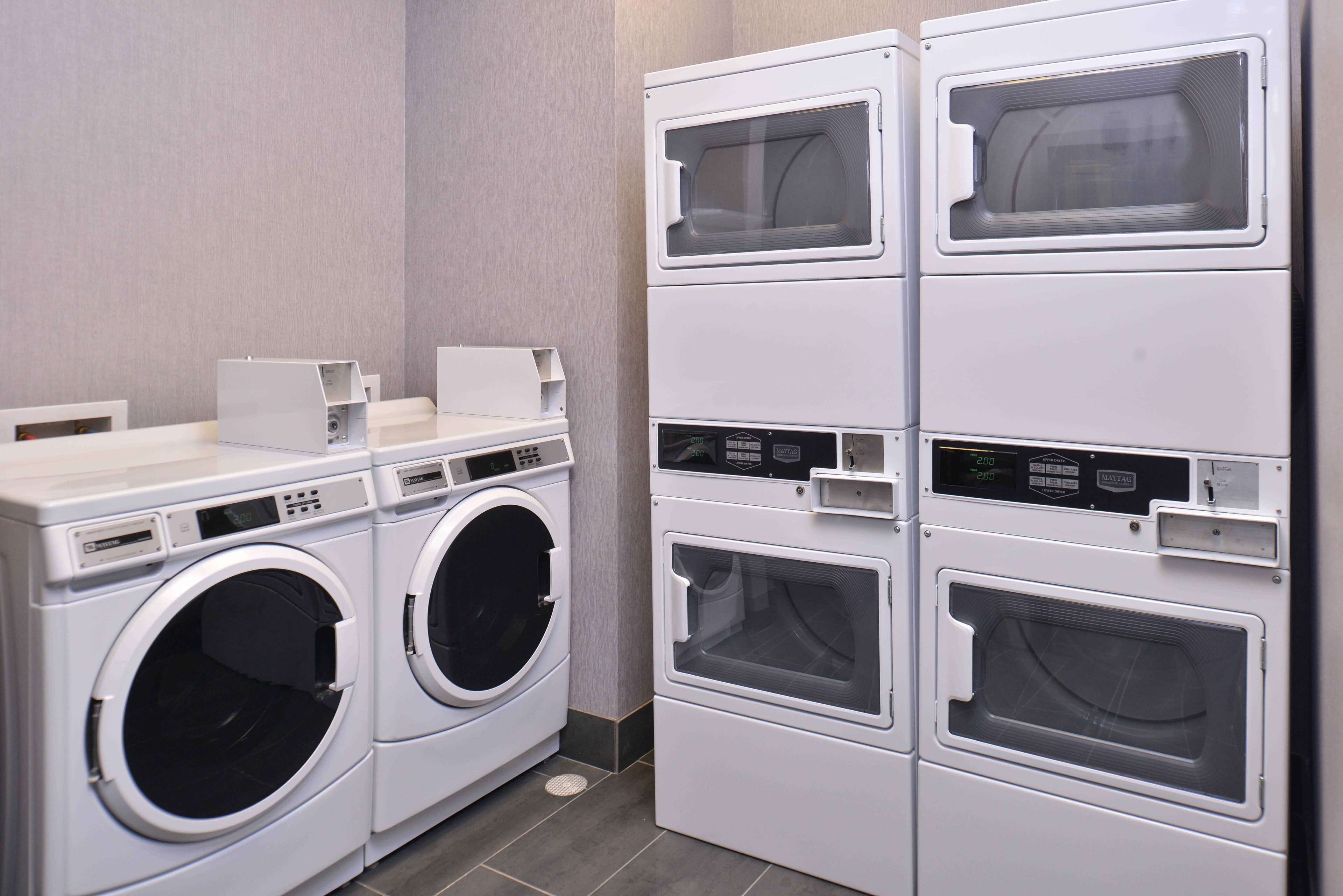 Une buanderie équipée de machines à laver et de sèche-linge superposés.