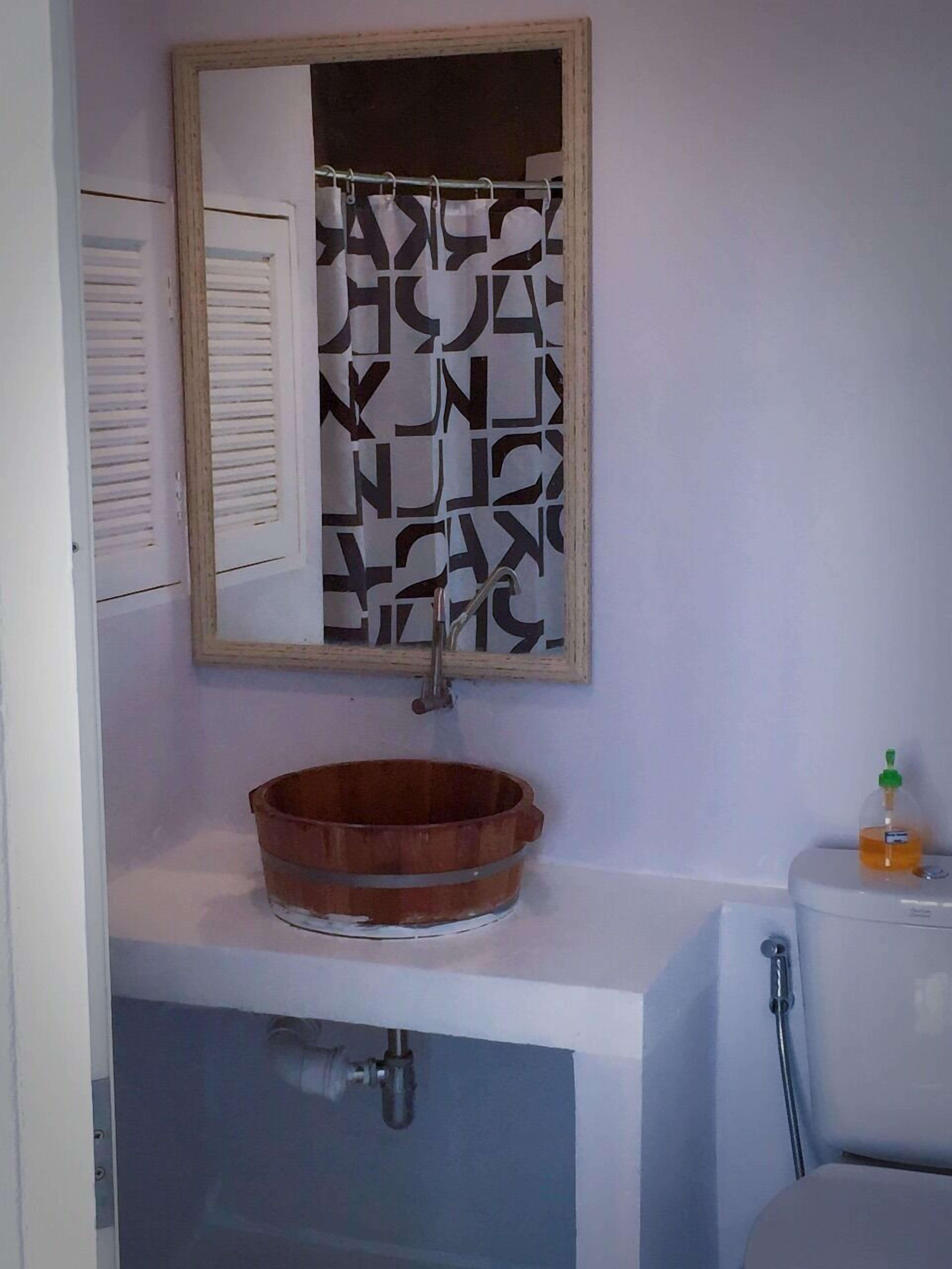 Une salle de bain avec un lavabo en bois, un miroir et des toilettes.