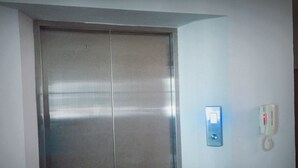 A closed elevator door with a wall-mounted intercom and a phone. - Sirin Loft Resident (Chiang Mai)