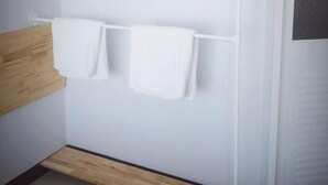 A bathroom with a wooden bench, a white towel rack, and a white door. - Sirin Loft Resident (Chiang Mai)