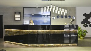 A reception desk with a 'RECEPTION' sign, a wall-mounted clock, and a potted plant. - Arus Hotel (Eskisehir)