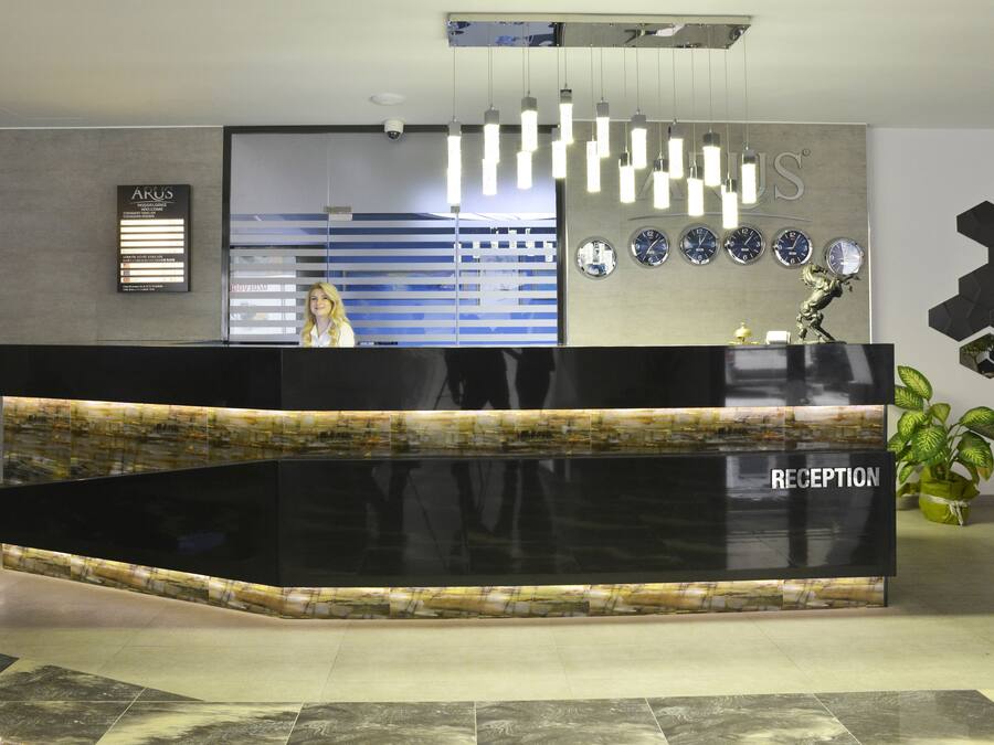 A reception desk with a 'RECEPTION' sign, a wall-mounted clock, and a potted plant.