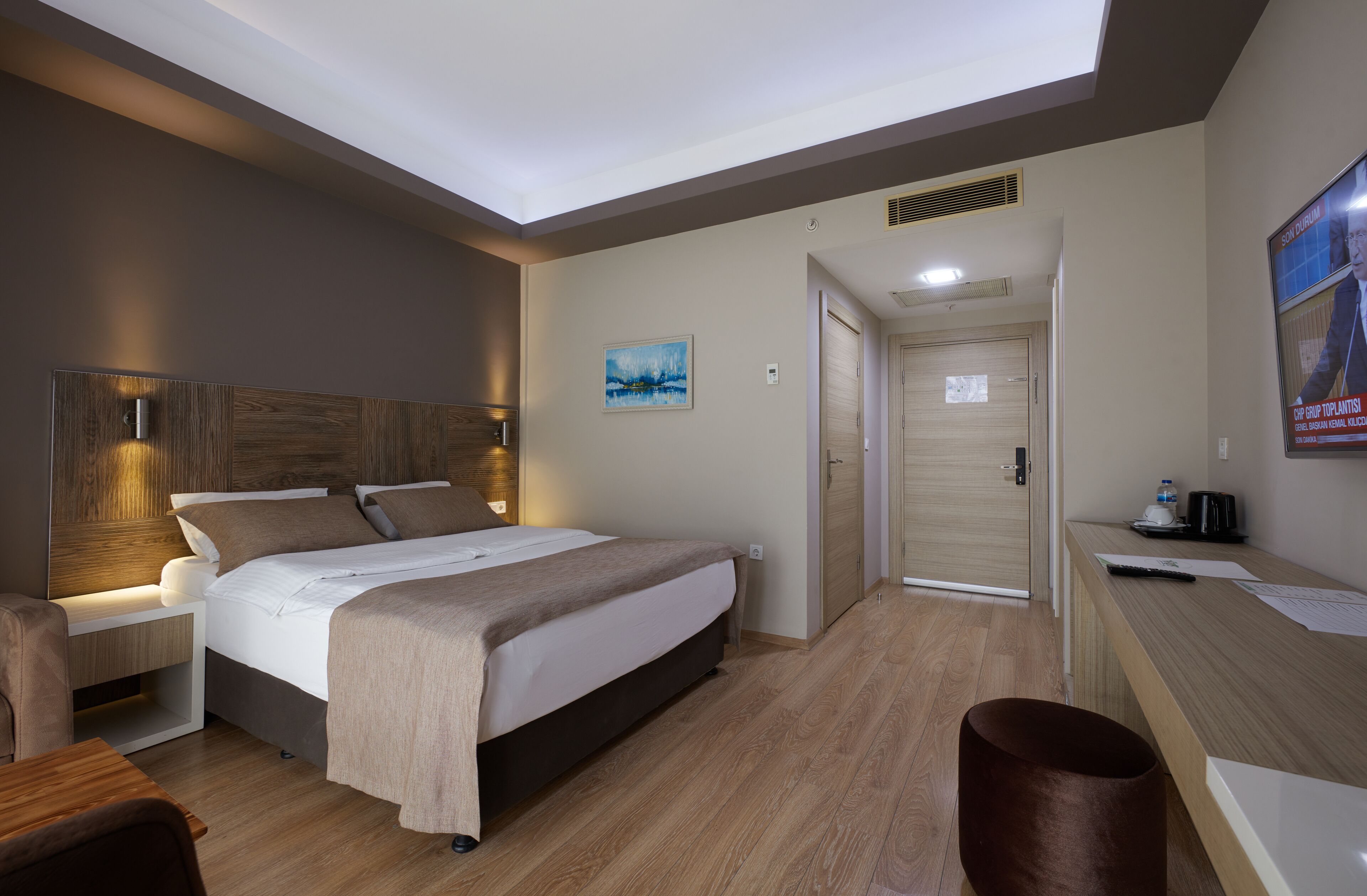 A modern hotel room with a large bed, bedside tables, a desk, and a chair.