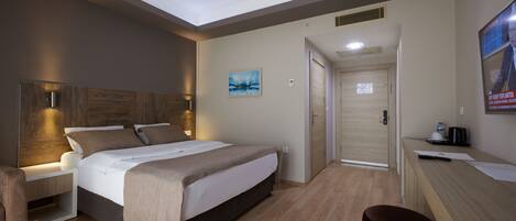 A modern hotel room with a large bed, bedside tables, a desk, and a chair.