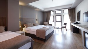 A modern hotel room with two beds, a desk, a chair, and a large window. - Arus Hotel (Eskisehir)