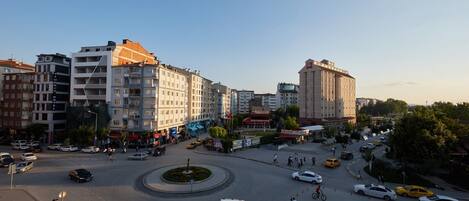 A city square with a roundabout, surrounded by multi-story buildings including a hotel and a bank.