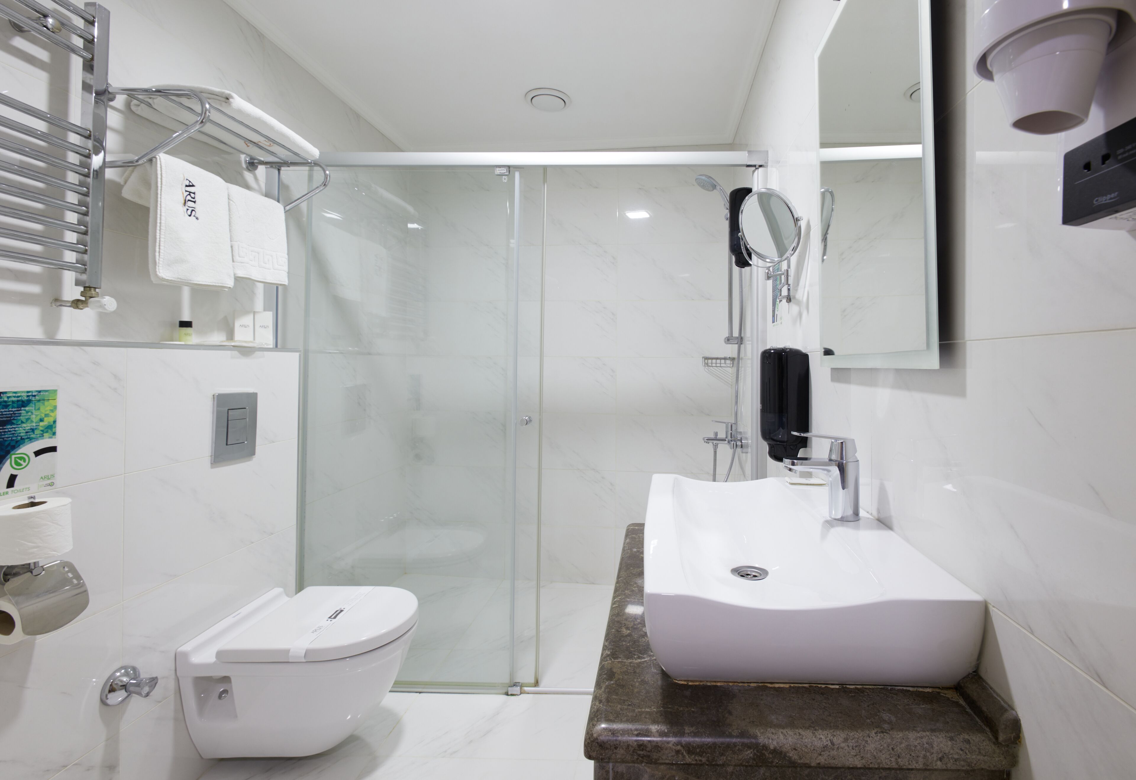 A modern bathroom with a glass-enclosed shower, a white sink, and a toilet.