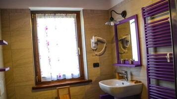 A bathroom with a window, a sink, a mirror, and a towel rack.
