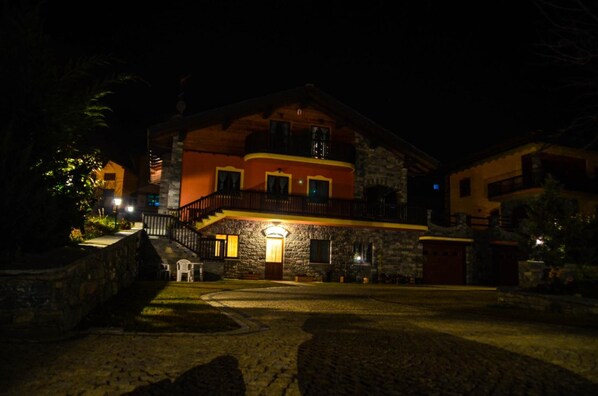 Un edificio de piedra con balcón y entrada iluminada.