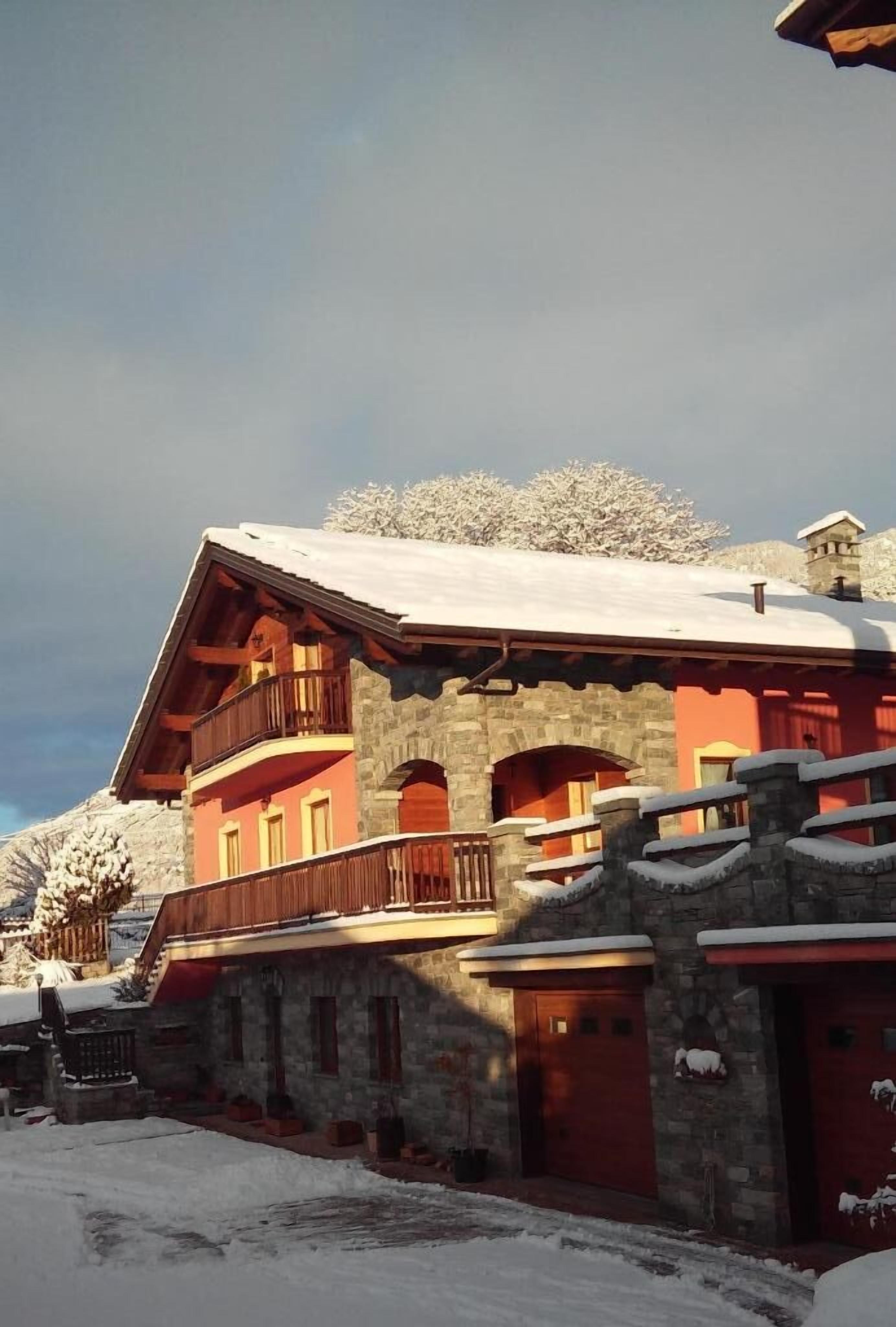 Un edificio de varios pisos con muros de piedra y balcones de madera, rodeado de nieve.