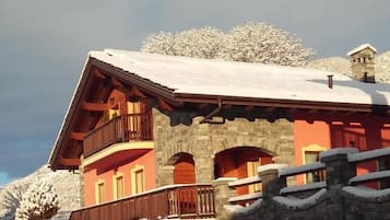 A multi-story building with stone walls and wooden balconies, surrounded by snow.