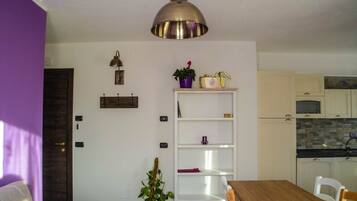 Una cocina compacta con armarios blancos, encimera de madera y una lámpara colgante.