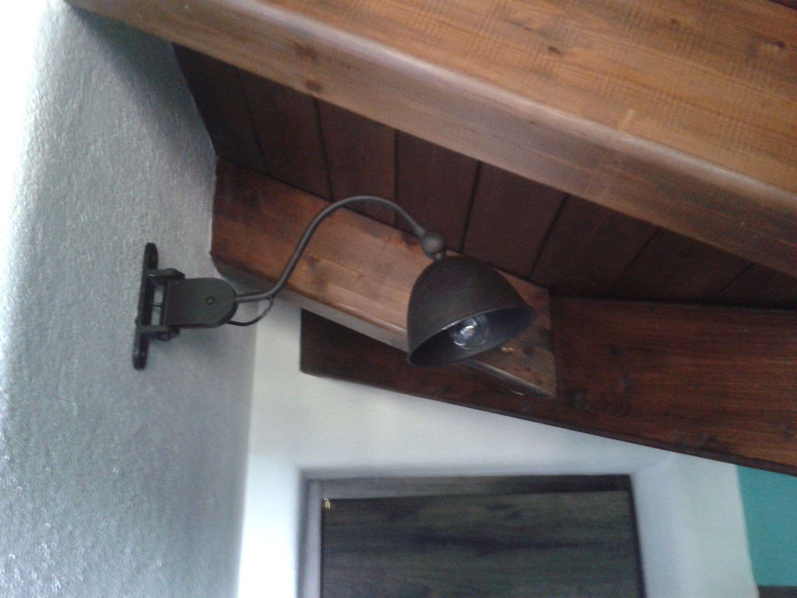 En väggmonterad lampa med en träbalk ovanför.