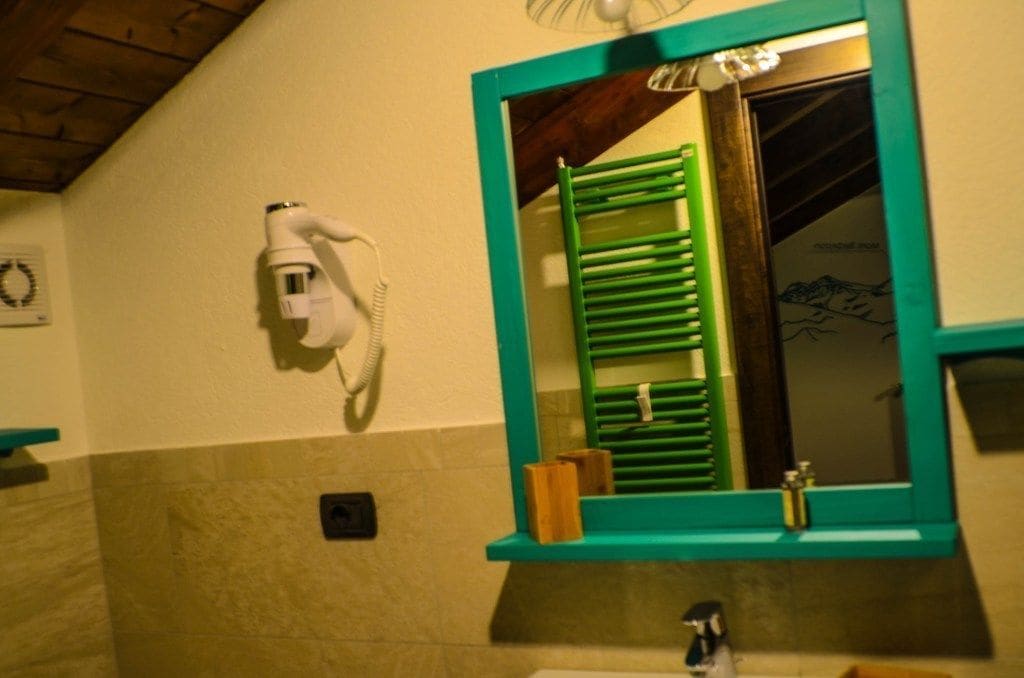 Ein Badezimmer mit einem spiegel mit grünem Rahmen, einem an der Wand montierten Fön und einem Handtuchhalter.