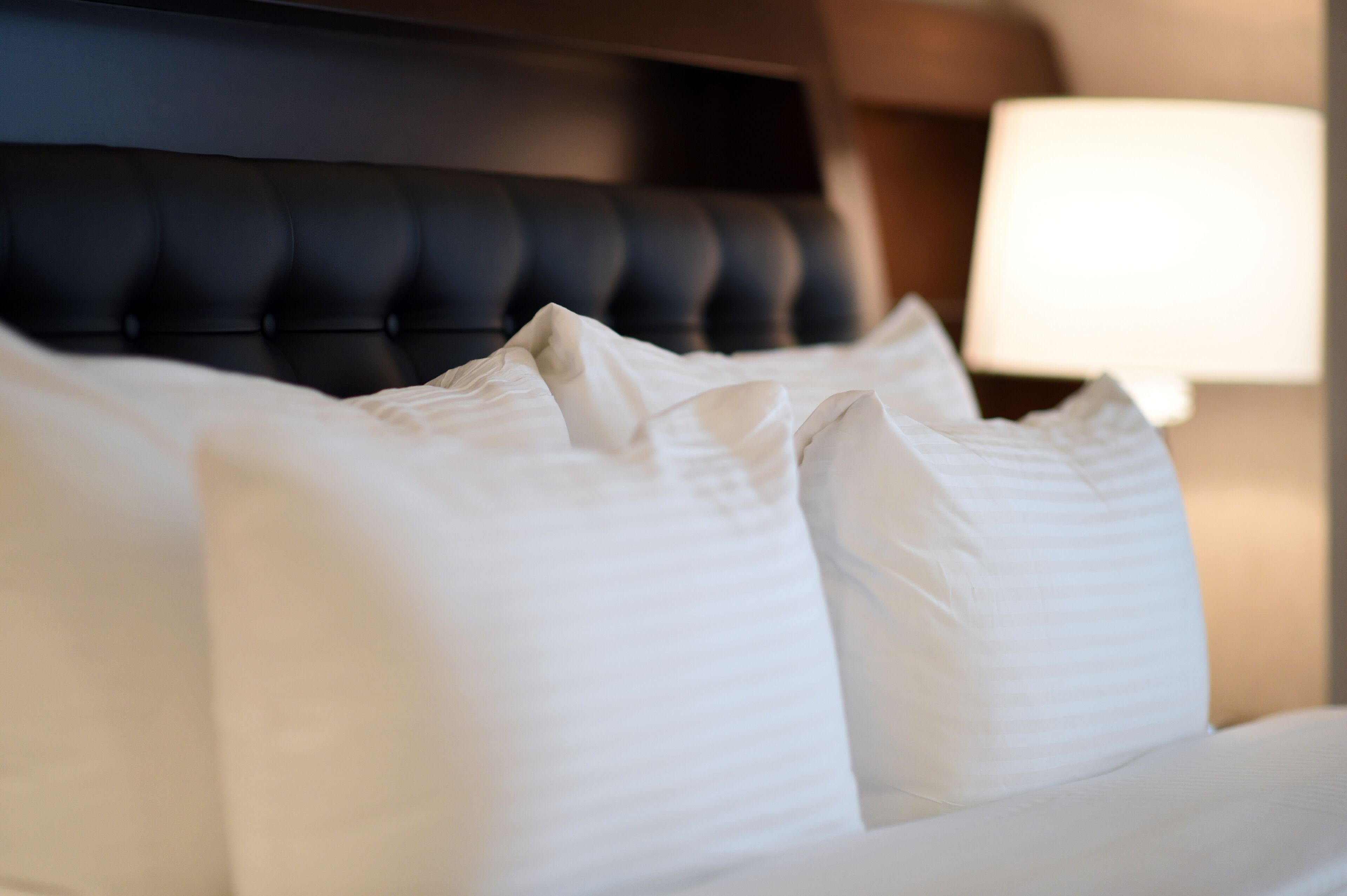 A bed with white linens and a tufted headboard.