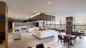 A modern kitchen with a central island, dining area with tables and chairs, and large windows offering a view of the city. - Wirye Militopiahotel By Marine (Seongnam)