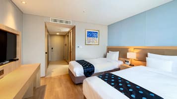 A hotel room with two beds, a desk, a TV, and a painting on the wall.