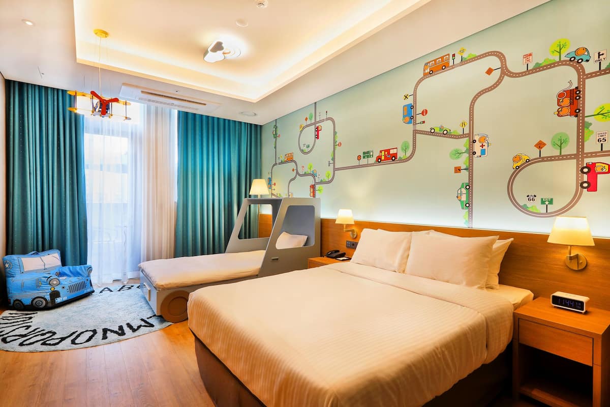 A hotel room with two beds, a map mural, a toy car, and a clock on the nightstand.