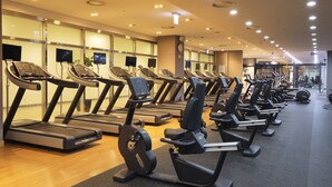 A gym with multiple treadmills and elliptical machines, a wooden floor, and a modern ceiling with recessed lighting. - Wirye Militopiahotel By Marine (Seongnam)