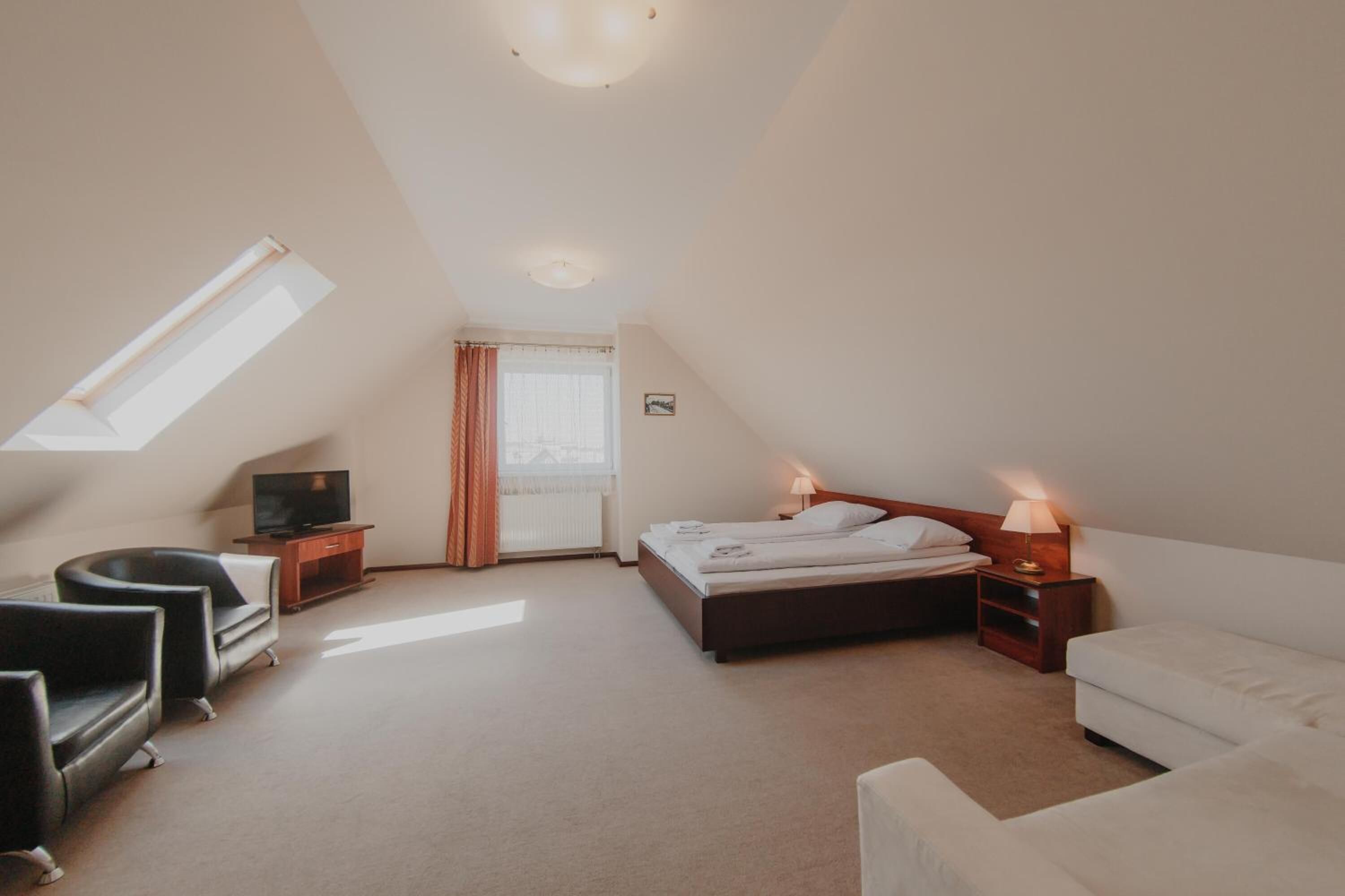 Une chambre à coucher avec un lit, des tables de chevet, une télévision et un canapé.