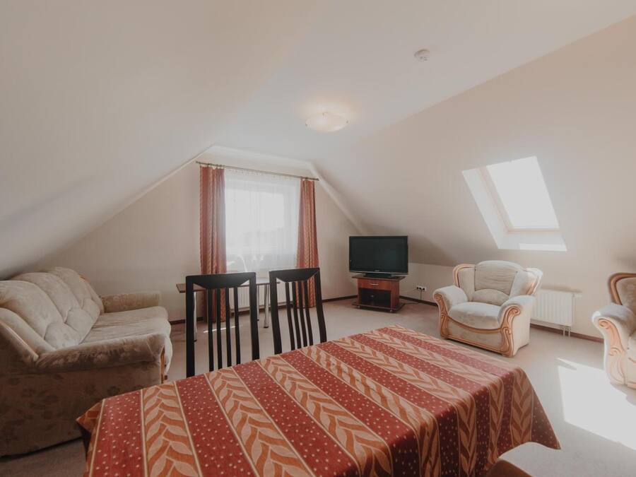 A cozy, well-lit room with a dining table, two chairs, a sofa, and a TV.