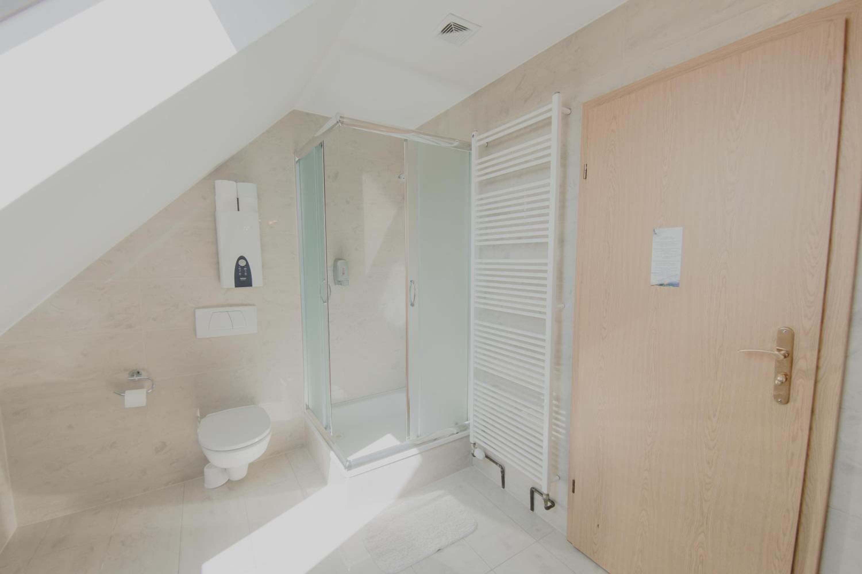 Un baño con inodoro, ducha y puerta de madera.