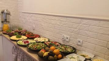 A buffet table with various dishes, including salads, fruits, and other food items.
