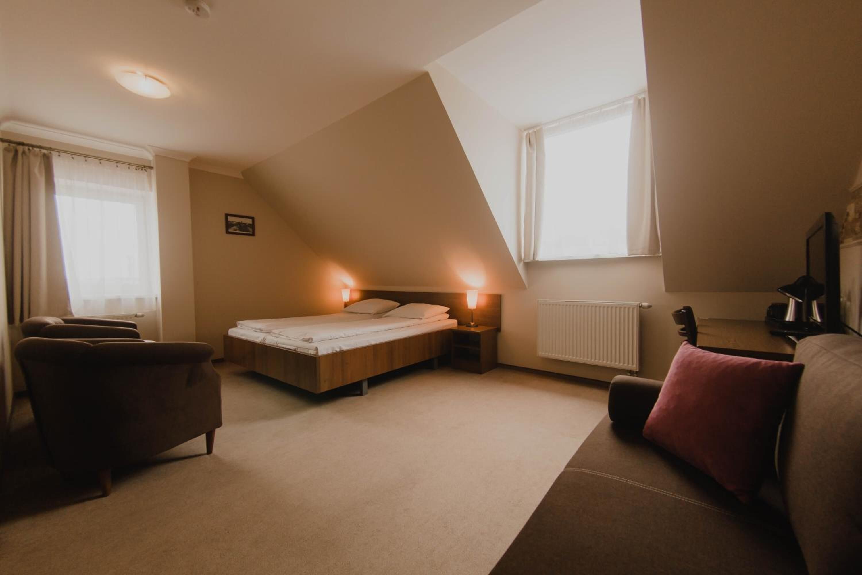 Een slaapkamer met een bed, nachtkastjes, een bureau en een stoel.
