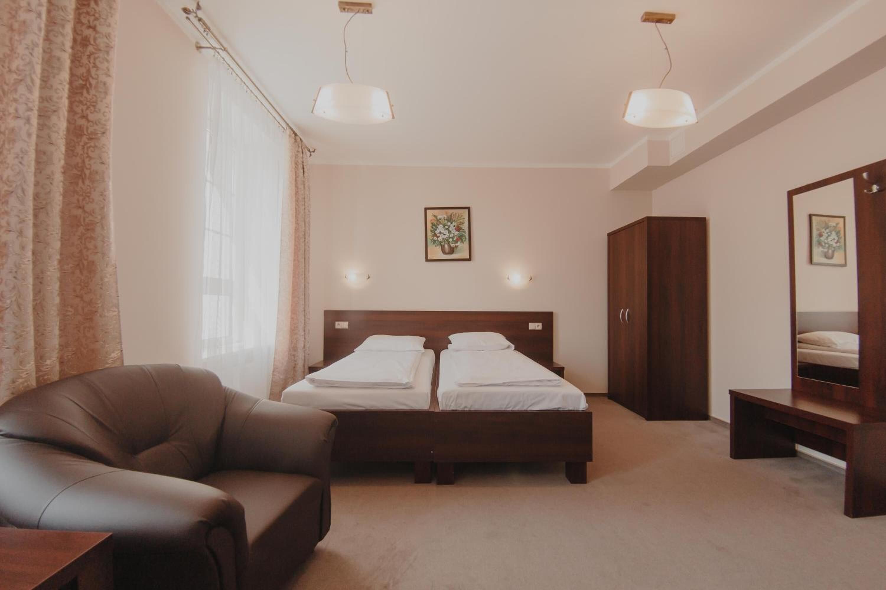 Een slaapkamer met een tweepersoonsbed, een houten garderobe, een leren fauteuil en een nachtkastje.